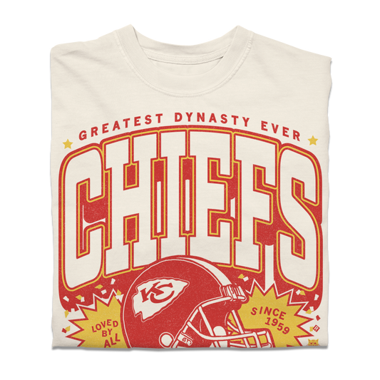 Heavyweight ivory t-shirt with a vintage-style Kansas City Chiefs graphic featuring a football helmet and the text Greatest Dynasty Ever, Chiefs, Loved by All, and Since 1959.