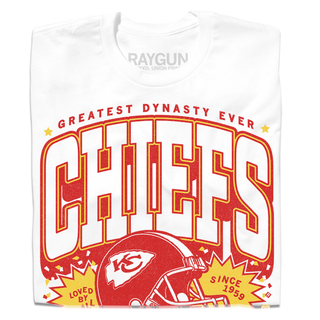 White RAYGUN T-shirt with red text GREATEST DYNASTY EVER above CHIEFS and a football helmet graphic, featuring the text LOVED BY ALL and SINCE 1959 for Chiefs Kingdom.