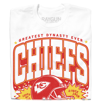 White RAYGUN T-shirt with red text GREATEST DYNASTY EVER above CHIEFS and a football helmet graphic, featuring the text LOVED BY ALL and SINCE 1959 for Chiefs Kingdom.