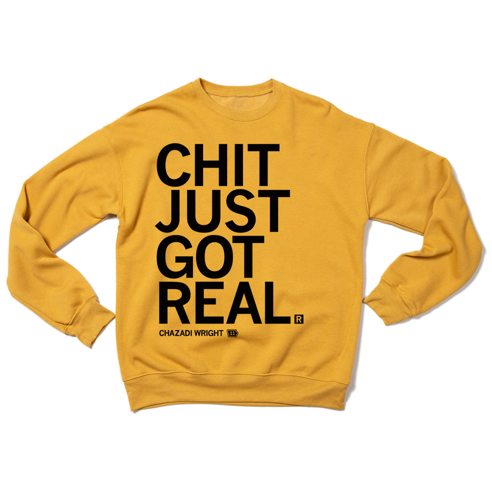 A folded heather mustard crewneck sweatshirt with left aligned black ink that reads "Chit Just Got Real. Chazadi Wright 11"