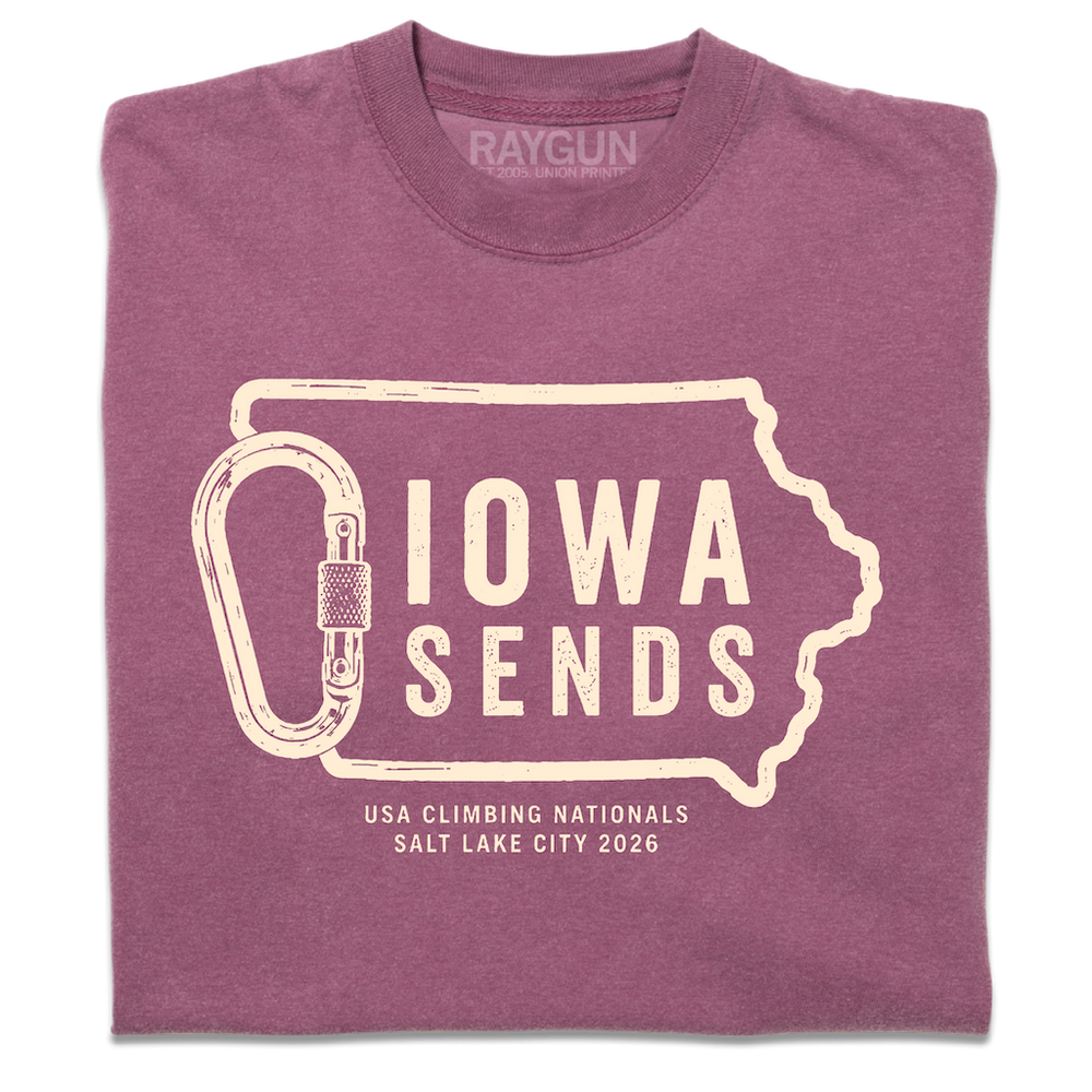 A folded Comfort Colors berry t-shirt with off white ink showing an outline of Iowa with it's western border being a carabiner. Large text inside the state outline says, "Iowa sends" and smaller text below reads "US Climbing Nationals. Salt Lake City 2026"