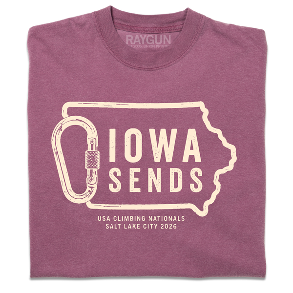A folded Comfort Colors berry t-shirt with off white ink showing an outline of Iowa with it's western border being a carabiner. Large text inside the state outline says, 