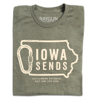 A folded heather military green t-shirt with off white ink showing an outline of Iowa with it's western border being a carabiner. Large text inside the state outline says, "Iowa sends" and smaller text below reads "US Climbing Nationals. Salt Lake City 2026"