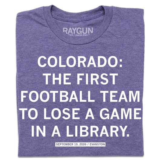 A folded heather purple t-shirt with centered white text that says, "COLORADO: THE FIRST FOOTBALL TEAM TO LOSE A GAME IN A LIBRARY. SEPTEMBER 19, 2026 / EVANSTON"