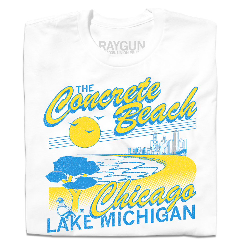 A folded white shirt with bright yellow and blue print that reads "The Concrete Beach. Chicago, Lake Michigan" with an illustration of a beachfront Chicago skyline and a pigeon in the corner.