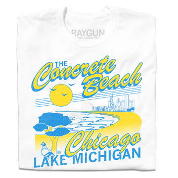 A folded white shirt with bright yellow and blue print that reads "The Concrete Beach. Chicago, Lake Michigan" with an illustration of a beachfront Chicago skyline and a pigeon in the corner.