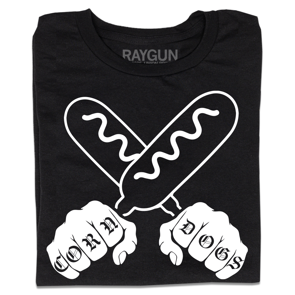 A folded black t-shirt with a white print illustration of two hands holding corndogs in an X shape with knuckle tattoos that spell out "CORNDOGS."