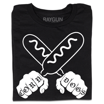 A folded black t-shirt with a white print illustration of two hands holding corndogs in an X shape with knuckle tattoos that spell out "CORNDOGS."