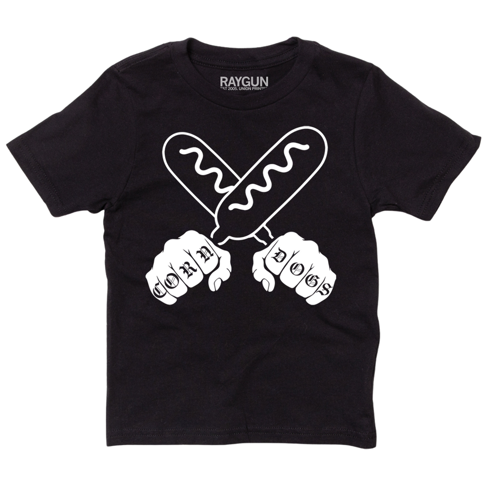 A youth sized black t-shirt with a white print illustration of two hands holding corndogs in an X shape with knuckle tattoos that spell out "CORNDOGS."