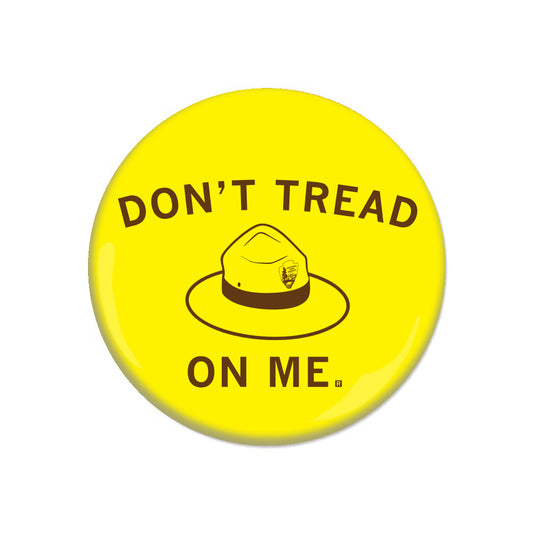 Yellow circular metal button featuring a National Park Service ranger hat in the center and the text DONT TREAD ON ME.
