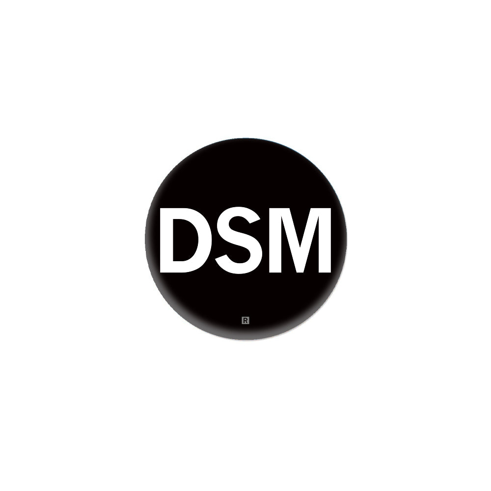 A black RAYGUN metal button featuring the white letters DSM with a small registration symbol below.