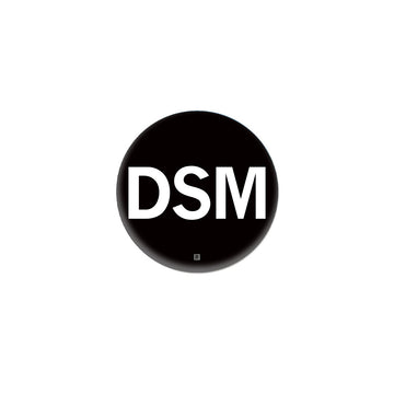 A black RAYGUN metal button featuring the white letters DSM with a small registration symbol below.