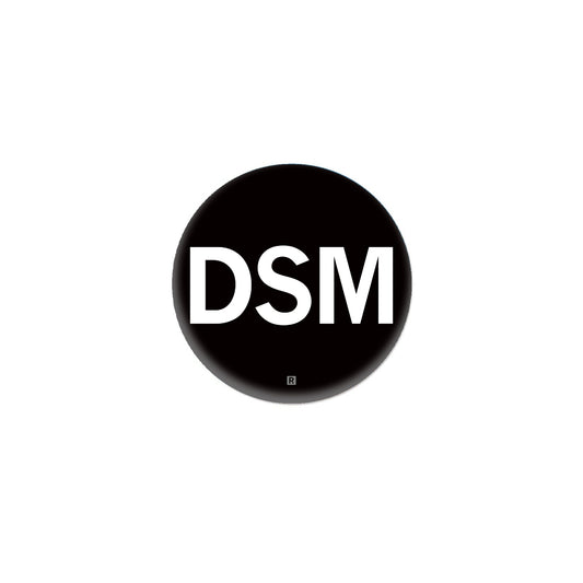 A black RAYGUN metal button featuring the white letters DSM with a small registration symbol below.