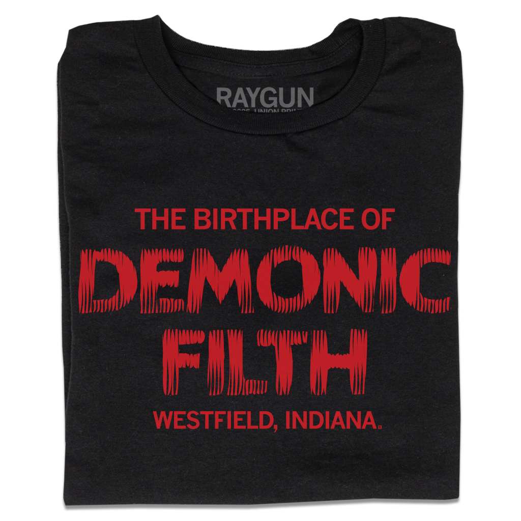 A folded black t-shirt with bright red ink in horror movie font that reads "The birthplace of demonic filth Westfield, Indiana."