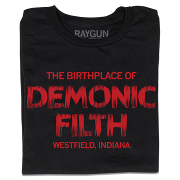 A folded black t-shirt with bright red ink in horror movie font that reads "The birthplace of demonic filth Westfield, Indiana."