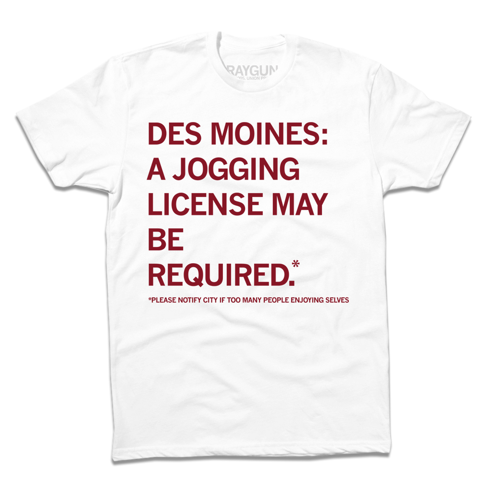 A white short-sleeve t-shirt with left-aligned cardinal ink text that says, "Des Mines: a jogging license may be required.* *Please notify city if too many people enjoying themselves."