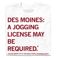A folded white t-shirt with cardinal ink that reads "Des Mines: a jogging license may be required.* *Please notify city if too many people enjoying themselves."