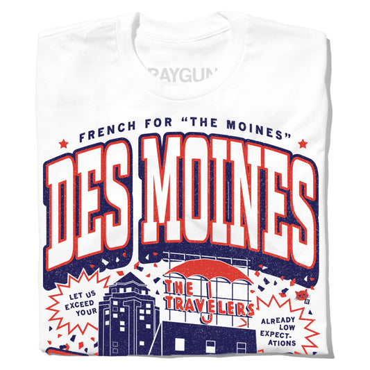 White RAYGUN t-shirt with a graphic that reads The Moines Des Moines above an illustration of the Des Moines skyline and the Travelers building with the text Let us exceed your already low expectations.