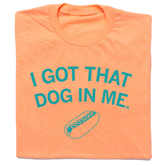 Orange RAYGUN t-shirt featuring the text I GOT THAT DOG IN ME in teal letters above an illustration of a hot dog.