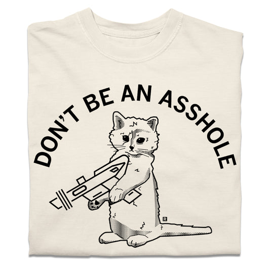 A folded off-white heavyweight t-shirt with curved black text that says, "DON'T BE AN ASSHOLE" above an illustration of a cat holding a raygun.