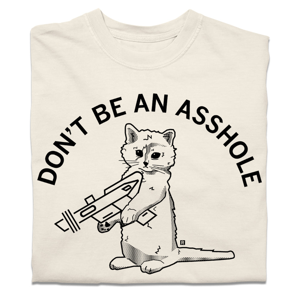 A folded off-white heavyweight t-shirt with curved black text that says, "DON'T BE AN ASSHOLE" above an illustration of a cat holding a raygun.