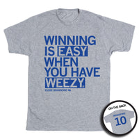 Short-sleeve heather grey t-shirt with left-aligned blue text that says, "WINNING IS EASY WHEN YOU HAVE WEEZY" with "ELOISE BRANDEWIE" in smaller text below. To the right of her name is an outline of Nebraska with the number "10" in its center. A circular picture to the bottom right shows the back of the shirt. The back is printed like a jersey with her last name above her number.