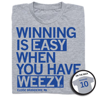 A folded heather grey t-shirt with left-aligned blue text that says, "WINNING IS EASY WHEN YOU HAVE WEEZY" with "ELOISE BRANDEWIE" in smaller text below. To the right of her name is an outline of Nebraska with the number "10" in its center. A circular picture to the bottom right shows the back of the shirt. The back is printed like a jersey with her last name above her number.