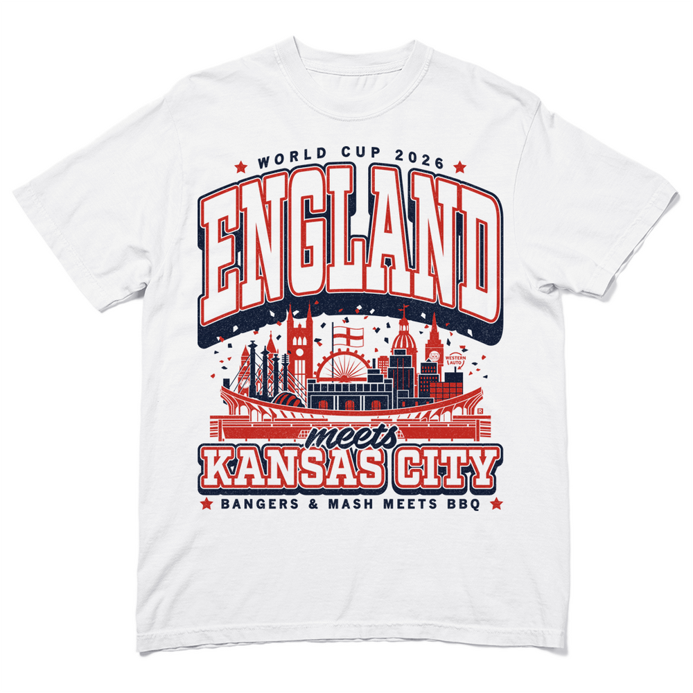 A white heavyweight t-shirt with navy and red ink. Text from top to bottom reads "World Cup 2026: England meets Kansas City. Bangers &amp; mash meets bbq." In the center is an illustration mixing notable building from England and Kansas City together.