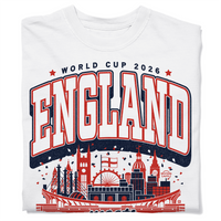 A folded white heavyweight t-shirt with navy and red ink. Text from top to bottom reads "World Cup 2026: England meets Kansas City. Bangers &amp; mash meets bbq." In the center is an illustration mixing notable building from England and Kansas City together.