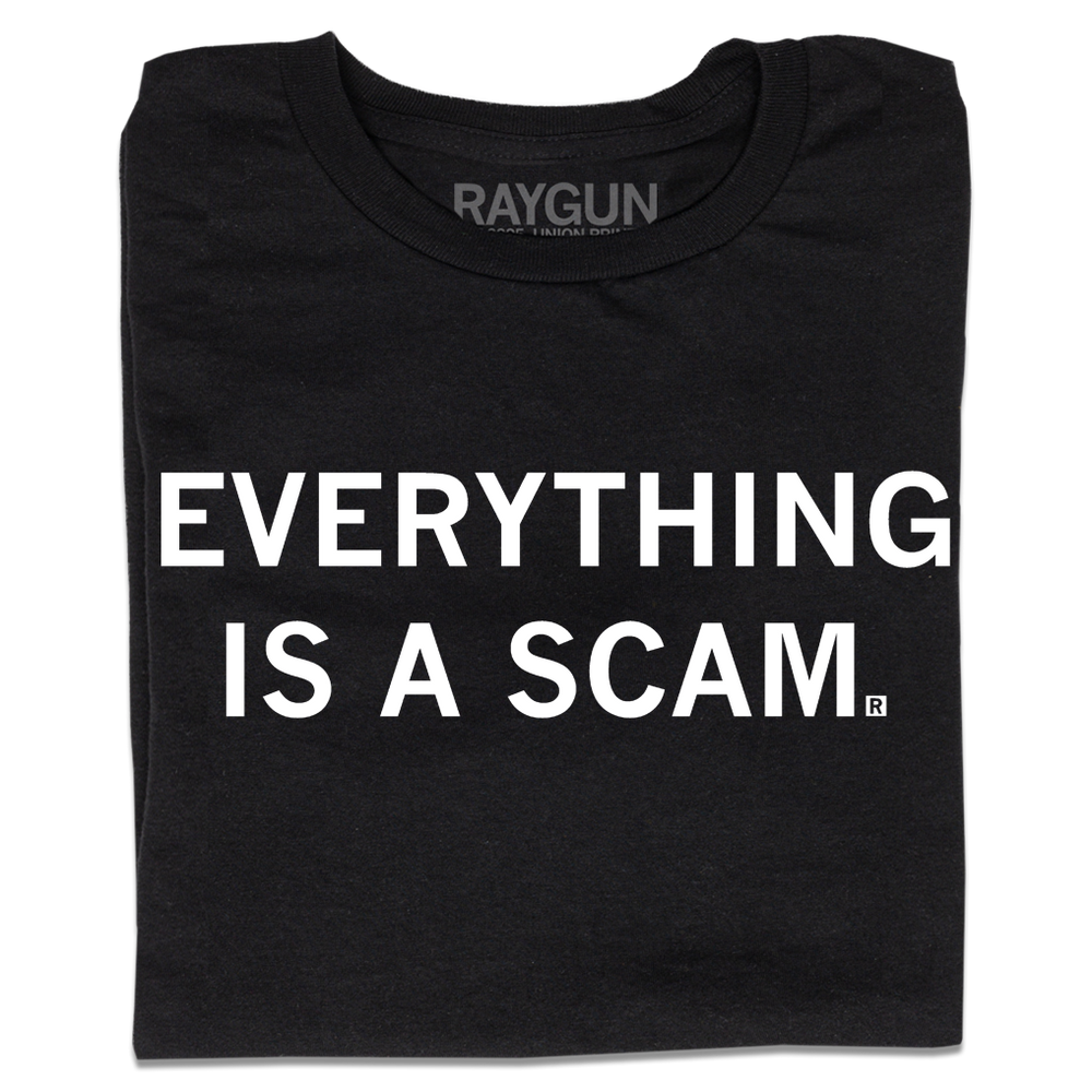 A folded black t-shirt with centered white ink text that says, "Everything is a scam."