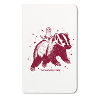 Notebook with a maroon ink graphic of a cat wearing a cheese hat riding a giant badger above the text "The Badger State"