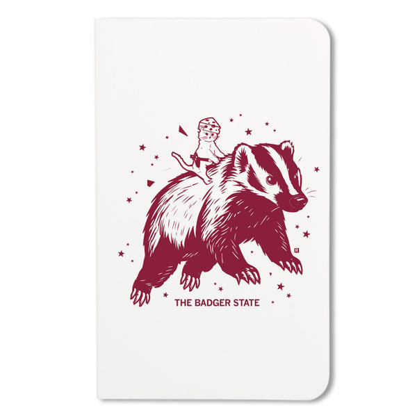 Notebook with a maroon ink graphic of a cat wearing a cheese hat riding a giant badger above the text 