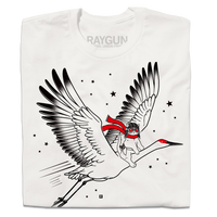 A folded dull white t-shirt with black and bright red ink depicting RAYGUN's cat mascot riding a giant crane through the sky while wearing a pilot helmet and a scarf.