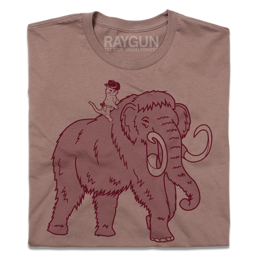 A mauve Gary the Cat Shiitake T-shirt featuring a graphic of a small cat in a cowboy hat riding on the back of a woolly mammoth.