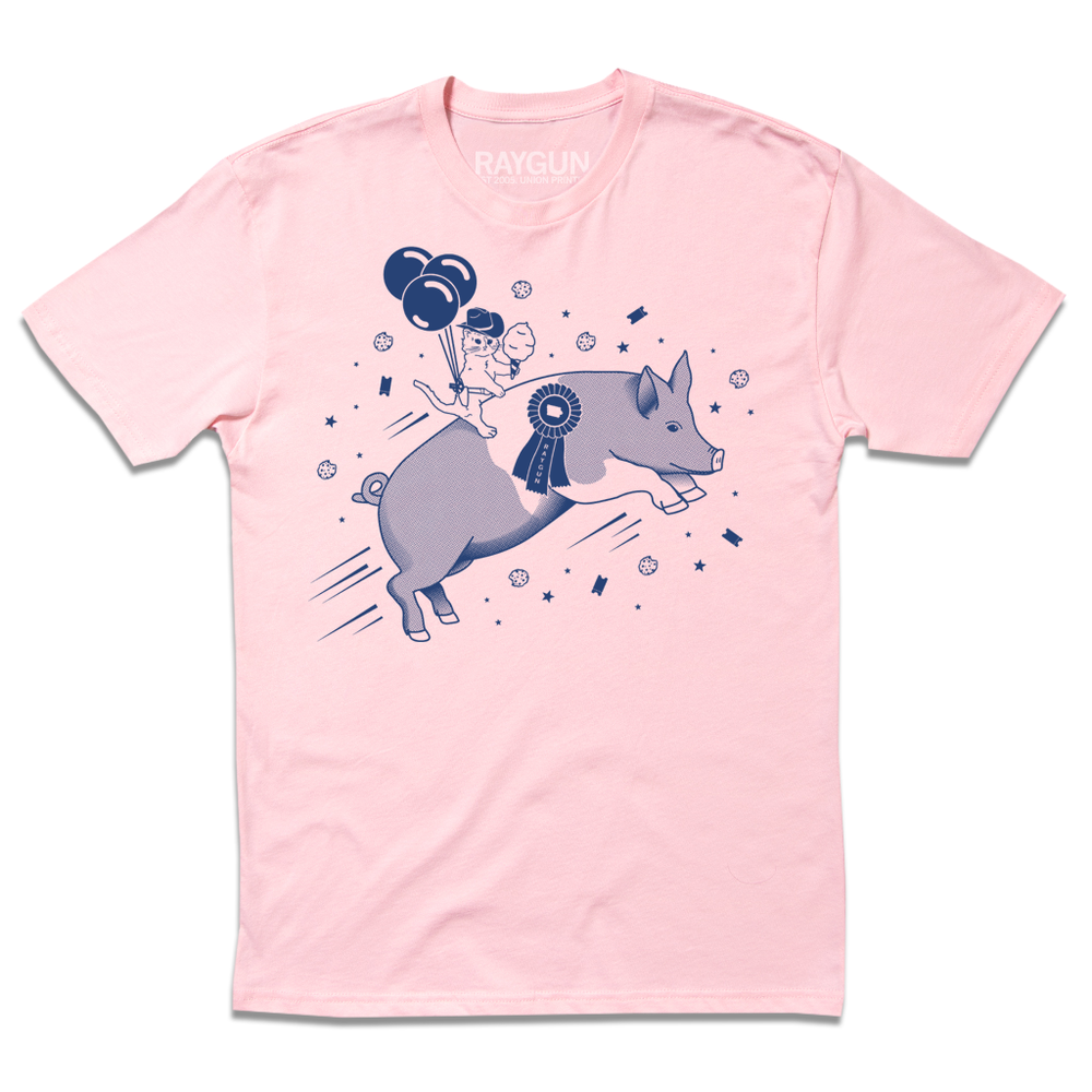 Light pink t-shirt with royal blue print depicting a hat with a cowboy hat holding cotton candy while riding a giant pig. There's also ticket stubs and bitten cookies flying by them and three balloons attached to the cat's holster.