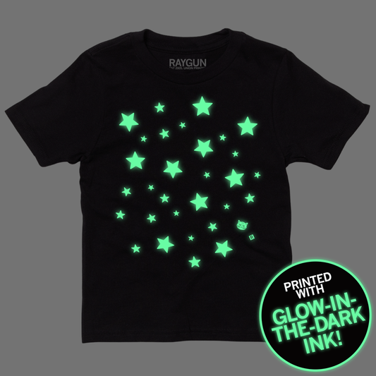 Black RAYGUN T-shirt featuring a scattered pattern of glow-in-the-dark stars and a small cat icon, with a circular badge noting it is printed with glow-in-the-dark ink.