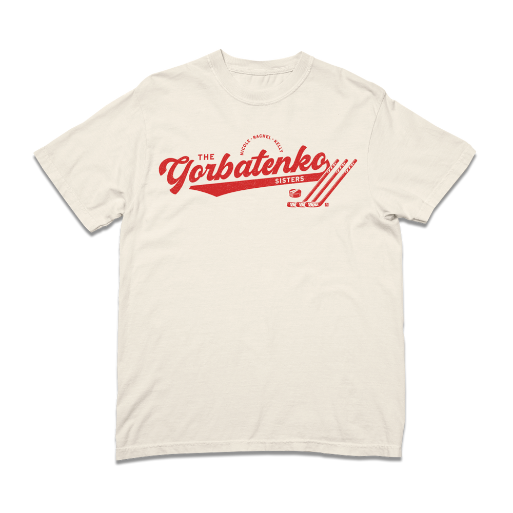 Red script text on an ivory comfort colors shirt that says, "The Gorbatenko Sissters. Nicole, Rachel, Kelly" with three hockey sticks and a puck laid flat.