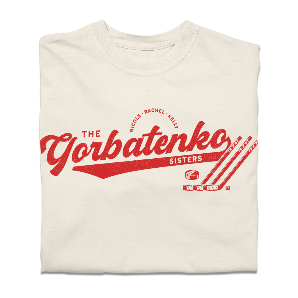 Red script text on an ivory comfort colors shirt that says, "The Gorbatenko Sissters. Nicole, Rachel, Kelly" with three hockey sticks and a puck.