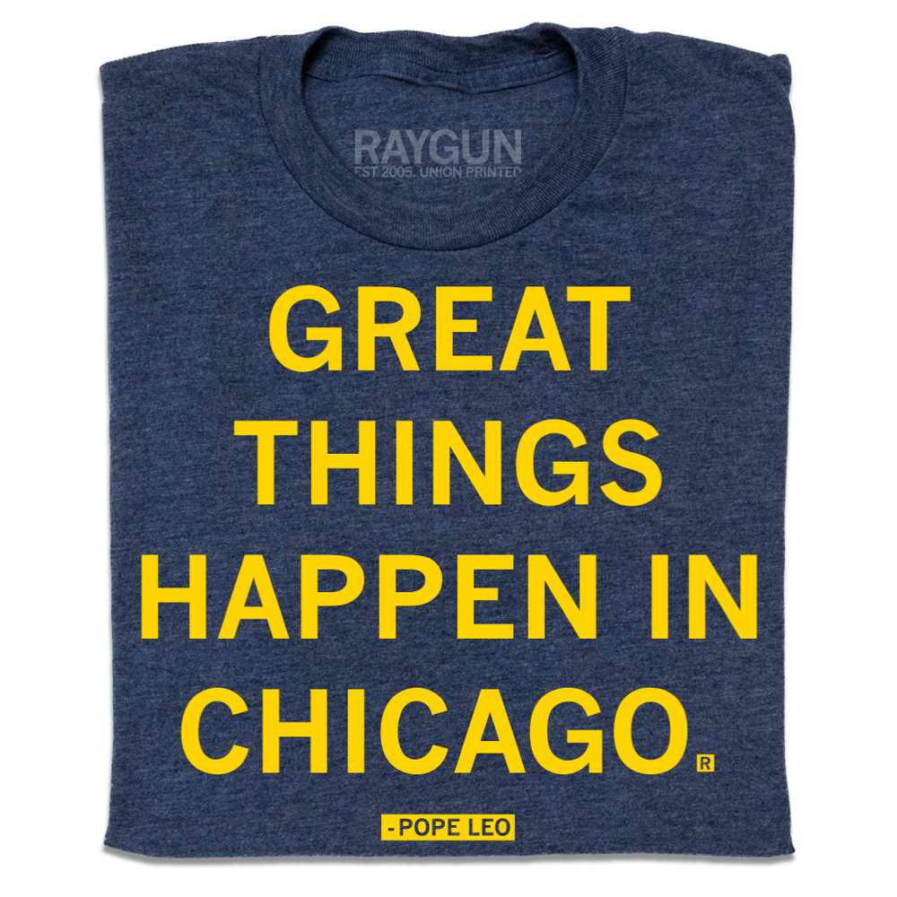 A folded heather navy t-shirt with centered yellow ink text that says, "GREAT THINGS HAPPEN IN CHICAGO. - POPE LEO."