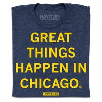 A folded heather navy t-shirt with centered yellow ink text that says, "GREAT THINGS HAPPEN IN CHICAGO. - POPE LEO."
