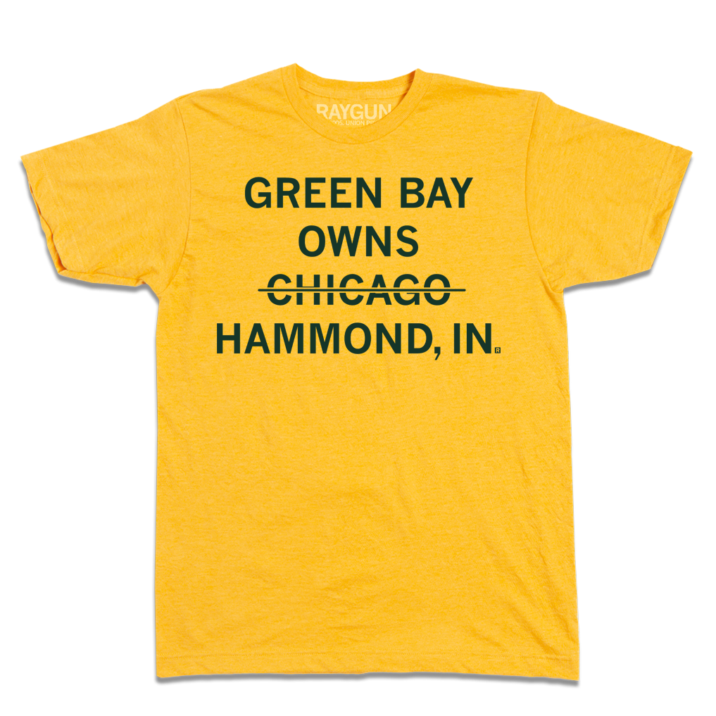 Heather mellow yellow t-shirt with centered, dark green text that says, "GREEN BAY OWNS CHICAOG HAMMOND, IN" with a line through "CHICAGO."