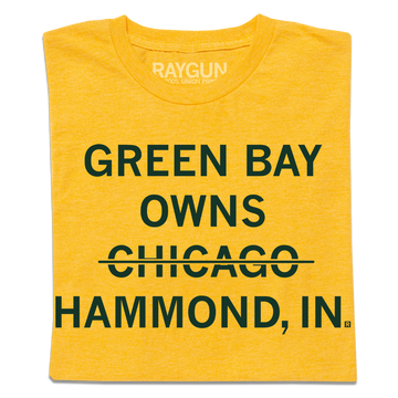 Folded heather yellow shirt with centered, dark green text that says, "GREEN BAY OWNS CHICAOG HAMMOND, IN" with a line through "CHICAGO."