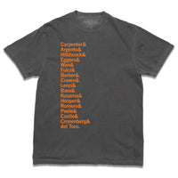 A short-sleeve grey heavyweight t-shirt with left-aligned orange ink in a long list that reads "Carpenter &amp; Argento &amp; Hitchcock &amp; Eggers &amp; Wan &amp; Fulci &amp; Barker &amp; Craven &amp; Lenzi &amp; Bava &amp; Kusama &amp; Hooper &amp; Romero &amp; Peele &amp; Castle &amp; Cronenberg &amp; del Toro."