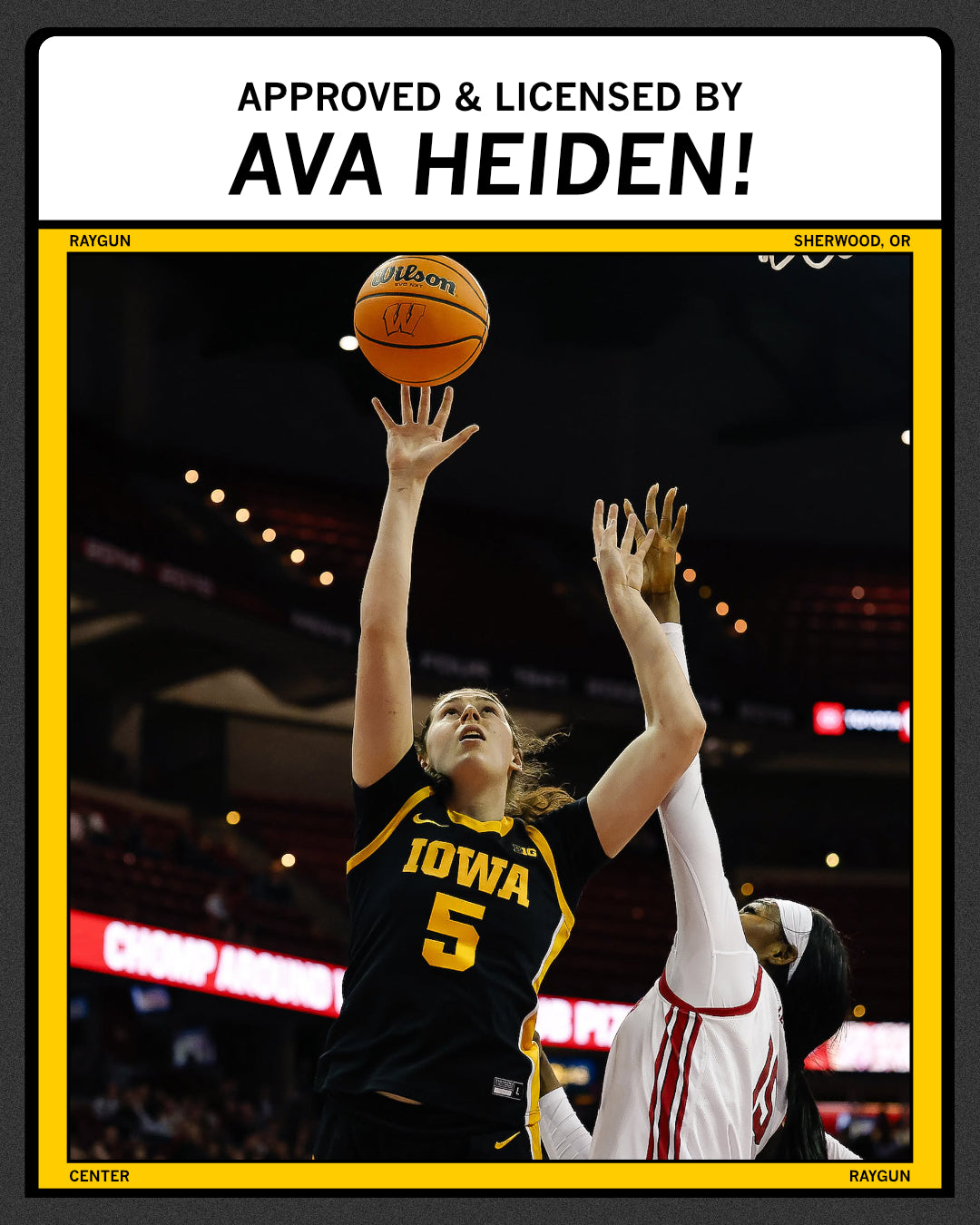 An Iowa basketball player wearing a golden yellow Heiden T-shirt shoots the ball while a defender reaches up to block her, with text at the top reading Approved & licensed by Ava Heiden!.