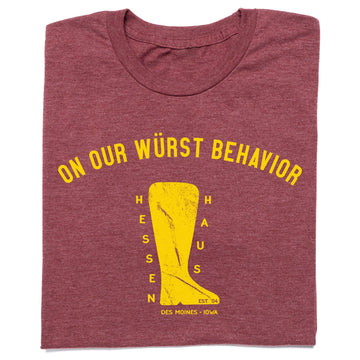 Heather burgundy t-shirt featuring the text ON OUR WÜRST BEHAVIOR in yellow above a graphic of a boot containing the words HESSEN HAUS, EST 04, and DES MOINES - IOWA.