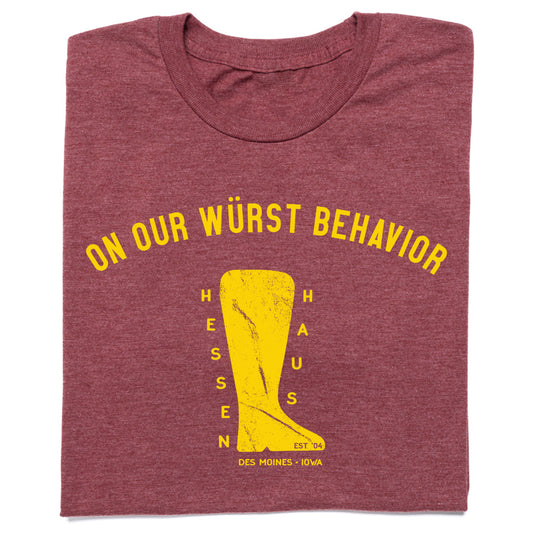 Heather burgundy t-shirt featuring the text ON OUR WÜRST BEHAVIOR in yellow above a graphic of a boot containing the words HESSEN HAUS, EST 04, and DES MOINES - IOWA.