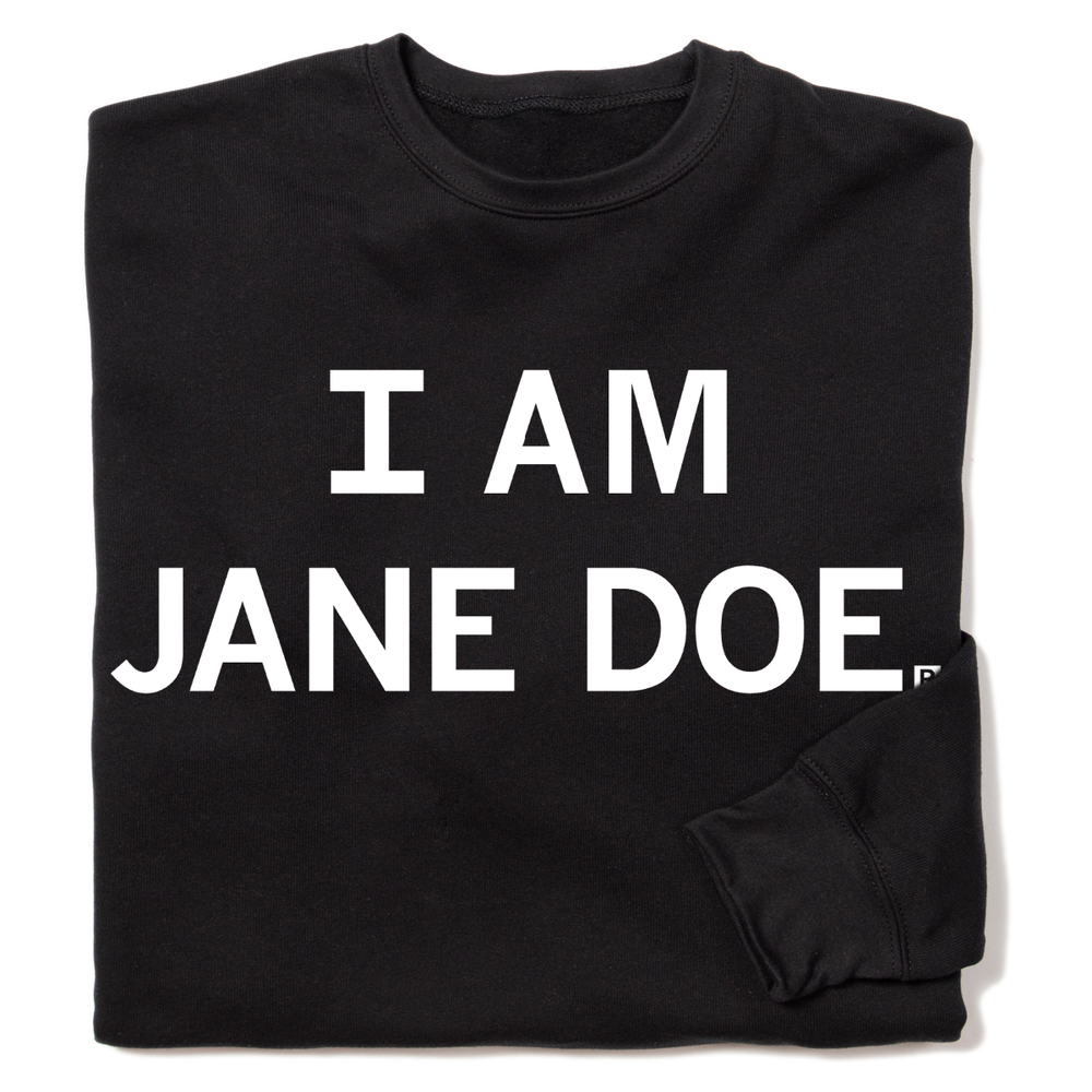 A folded black crewneck sweatshirt with centered white ink text that reads "I Am Jane Doe."