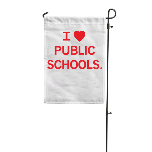 A white RAYGUN garden flag on a metal stand reading I [heart symbol] PUBLIC SCHOOLS in red text.
