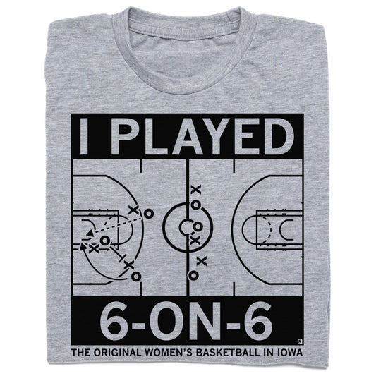A folded heather grey t-shirt with black ink print depicting a basketball court with text that says, "I played 6-on-6. The original women's basketball in Iowa."