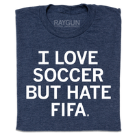 A folded heather navy t-shirt with centered white text that reads "I love soccer, but I hate FIFA."